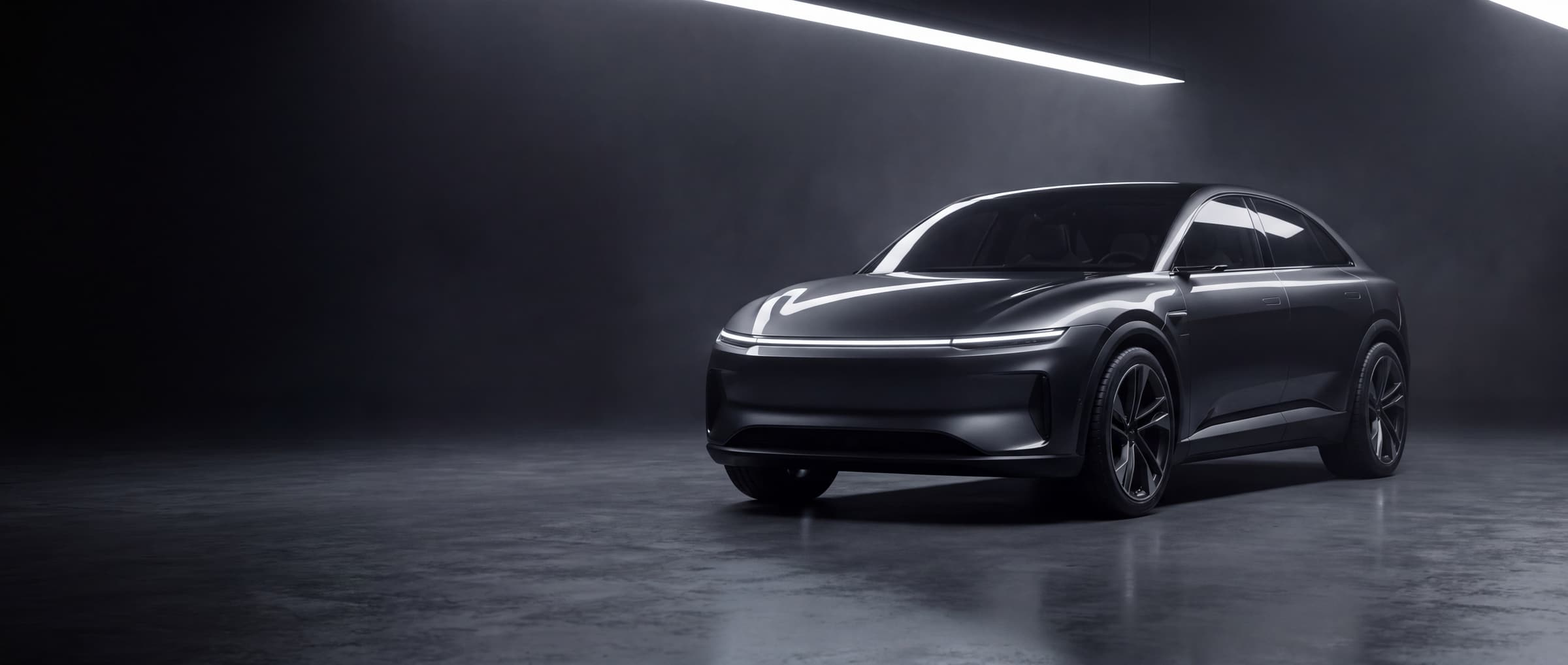 A sleek graphite concept car in a dark studio, lit by a single strip light