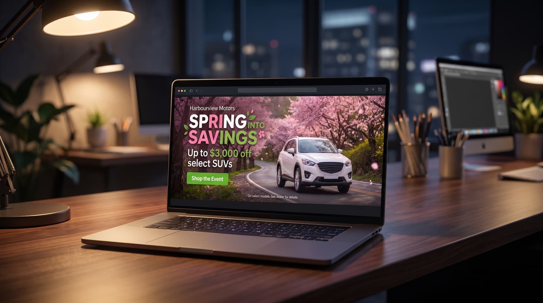 A laptop on a dark desk showing a spring sales event banner made in DealerAdGen